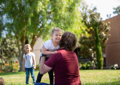 a young girl leaps into her fathers arms, excited to be caught by him.