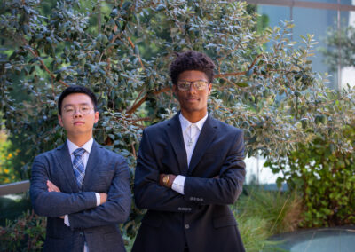 Two sharp dressed young men pose with arms crossed.