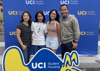 a family stands in-front of a UCI photo backdrop.